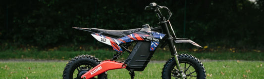 Kubbi K10 Pro kids' electric dirt bike in red, white and blue, side on by a hedge