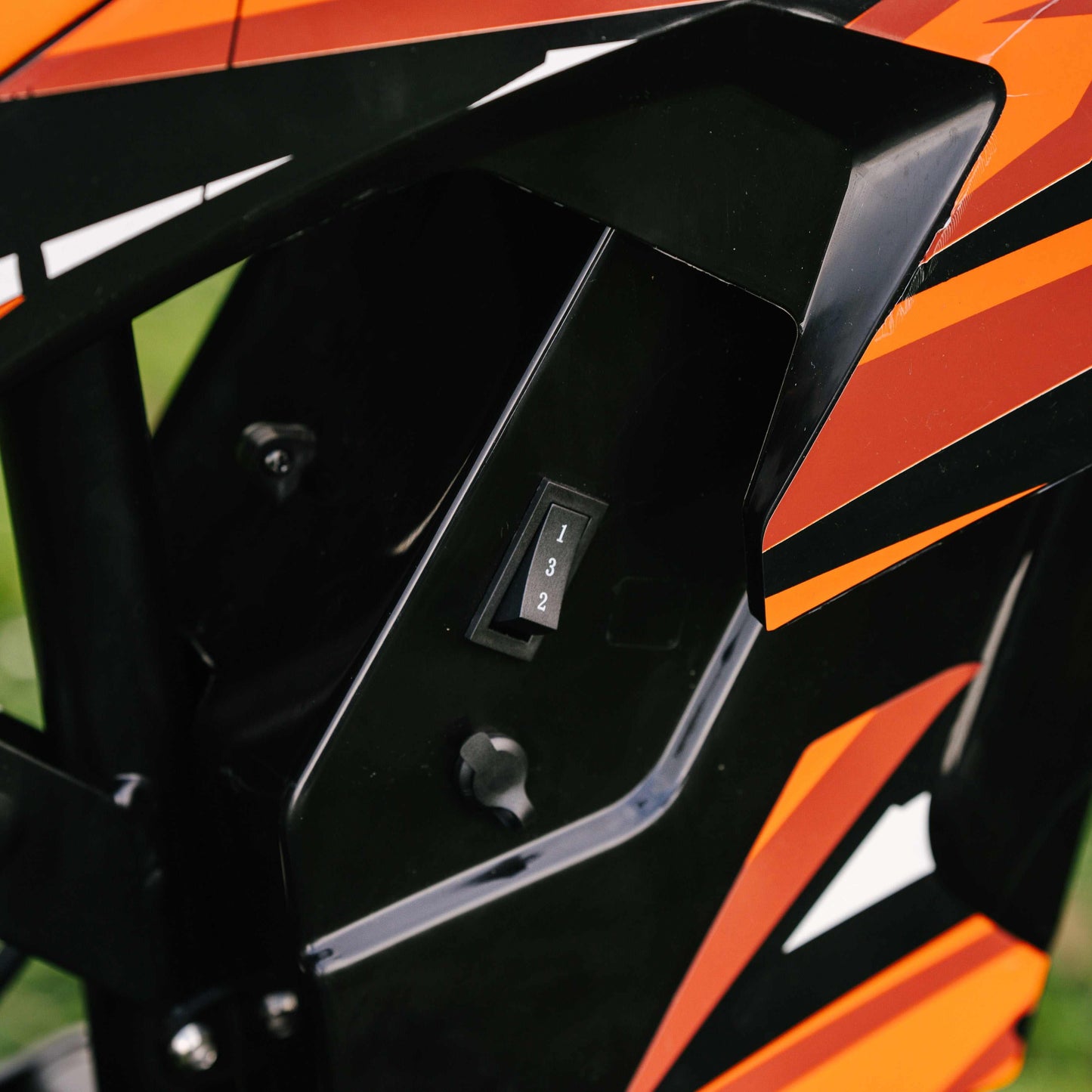 Close-up of Kubbi K7 Pro Dirt Bike speed gear switch on black and orange body panel