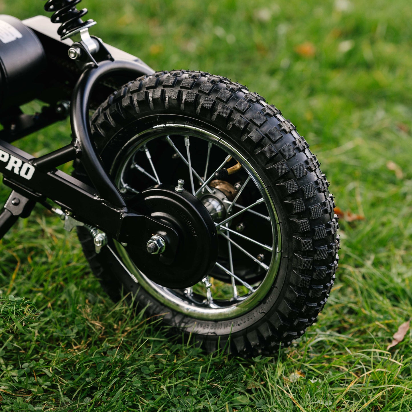 Close-up of Kubbi K7 Pro Dirt Bike rear 12-inch off-road tire on grass