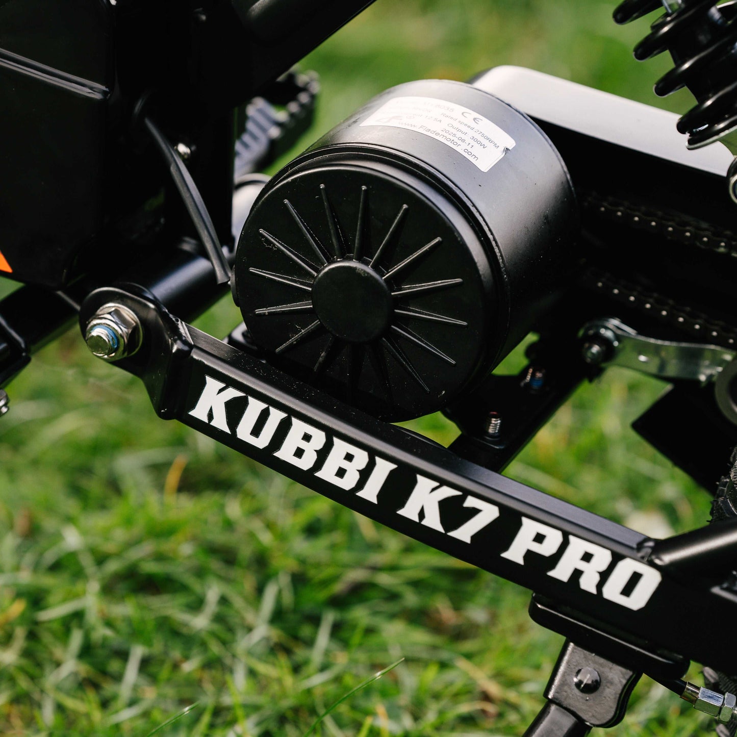 Close-up of Kubbi K7 Pro Dirt Bike motor and frame with logo on grassy background