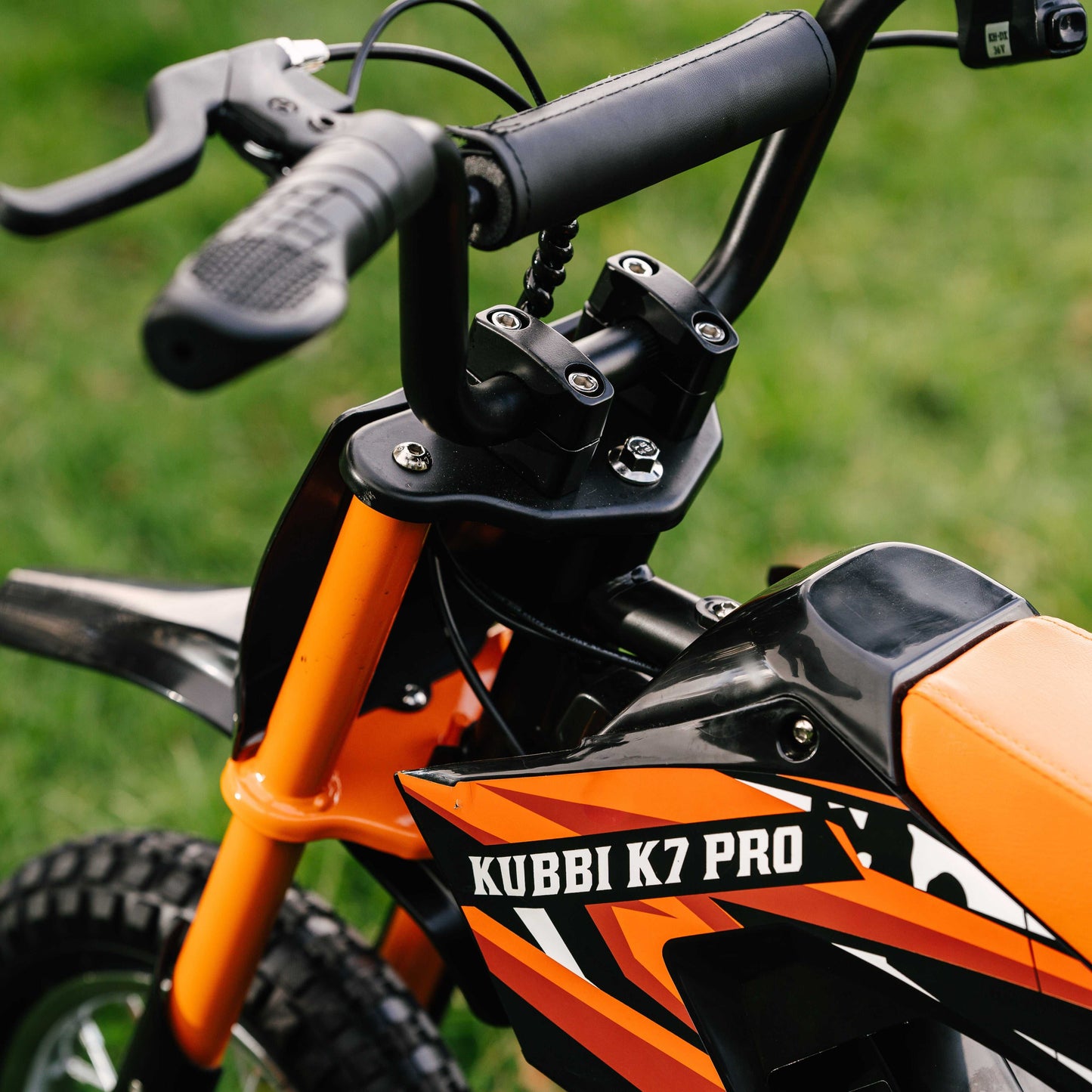 Close-up of Kubbi K7 Pro Dirt Bike handlebar and body with orange and black design for kids aged 5 to 13 years